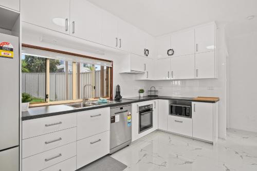 a white kitchen with white cabinets and a sink at Moana Ocean - C21 SouthCoast Holidays in Moana