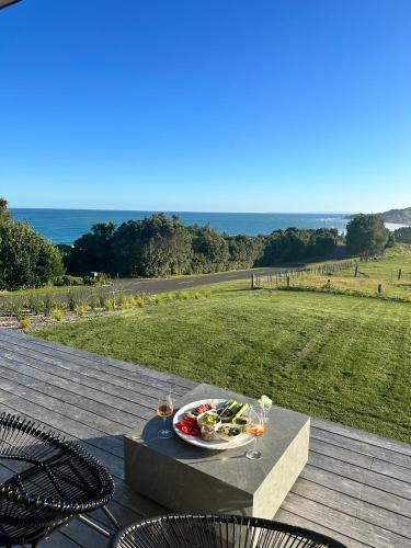 a table with a plate of food and wine glasses at Ocean + Country - Wainui Beach in Gisborne