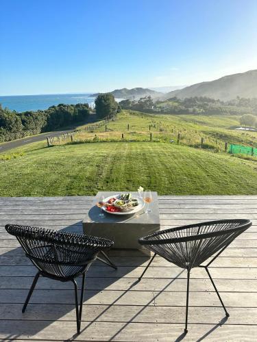a table and two chairs on a patio with a view at Ocean + Country - Wainui Beach in Gisborne