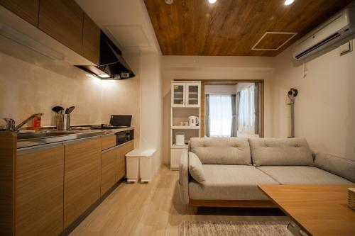 a living room with a couch and a kitchen at ASTORIA【2min from Asahikawa sta】 in Asahikawa