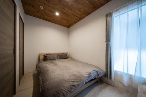 ASTORIA【2min from Asahikawa sta】 في اساهيكاو: غرفة نوم صغيرة بها سرير ونافذة