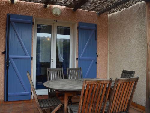 une table et des chaises sur une terrasse avec une porte bleue dans l'établissement Maison 3 pièces avec jardin, BBQ, animaux admis à Banyuls-sur-Mer - FR-1-225C-74, à Banyuls-sur-Mer