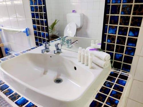 lavabo blanco en un baño con azulejos azules en Guesthouse in Suva en Suva