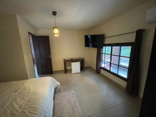 a bedroom with a bed and a flat screen tv at Pousada Som de Lumiar in Lumiar