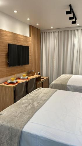 a hotel room with two beds and a flat screen tv at STUDIO PORTO PRIME PREMIUM in Porto De Galinhas