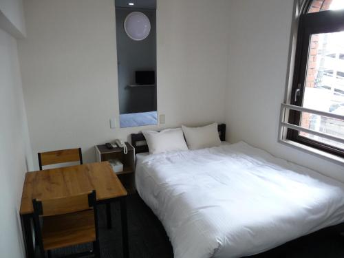 1 dormitorio con cama, mesa y ventana en Kurashiki Global Hotel, en Kurashiki