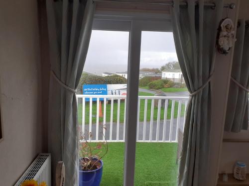 a window with a view of a balcony with green grass at 32 powys Quay west caravan park newquay ceredigion in New Quay