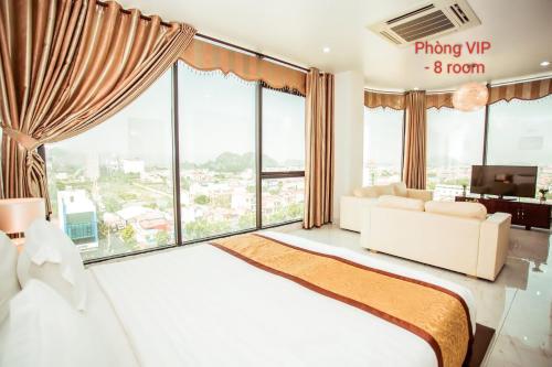 a bedroom with a large bed and large windows at Royal ANAN Hotel in Ninh Binh