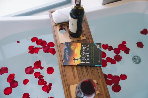a bottle of wine and a book on a table with flowers at Canary Dalat Hotel in Da Lat
