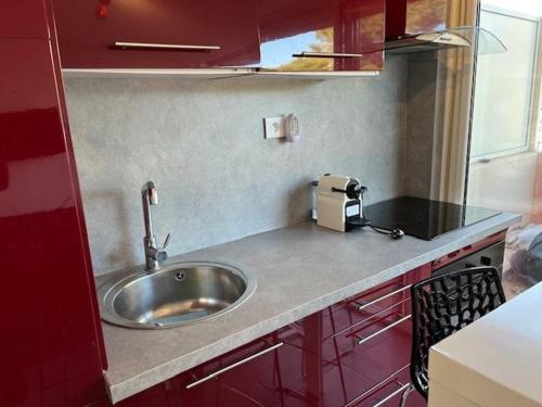 - une cuisine avec un évier et des placards rouges dans l'établissement Appartement T2 Climatisé au Cœur du Cap d'Agde, proche Port et Plages, 4 Personnes - FR-1-749-41, au Cap d'Agde