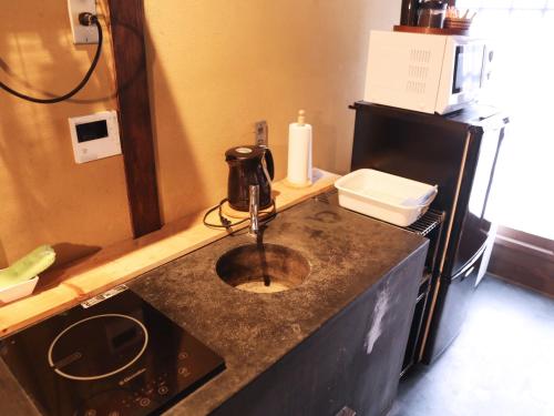 Una encimera de cocina con fregadero y microondas. en Zen Machiya Inn, en Kioto