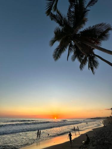 a sunset on a beach with a palm tree at Surf City Town House in La Libertad