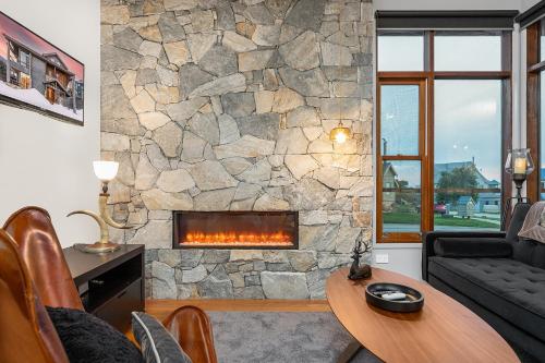 a living room with a stone wall with a fireplace at Triggerplant 1 in Dinner Plain