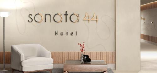 a living room with a white chair and a table at Sonata 44 Hotel Laureles in Medellín