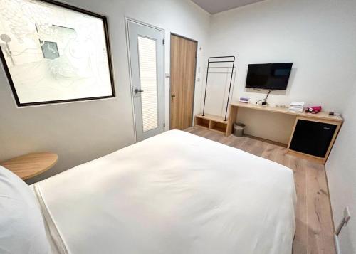 um quarto com uma cama branca e uma televisão em Yan Bin Hotel em Tainan
