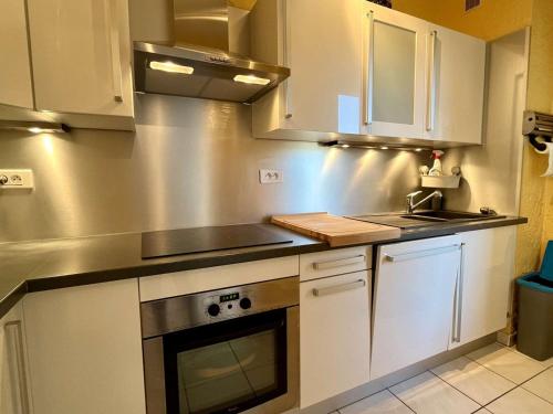 une cuisine avec des armoires blanches et un évier dans l'établissement Appartement climatisé à Cavalaire-sur-Mer, 2 pièces, parking privé, proche plages et commerces - FR-1-226B-181, à Cavalaire-sur-Mer