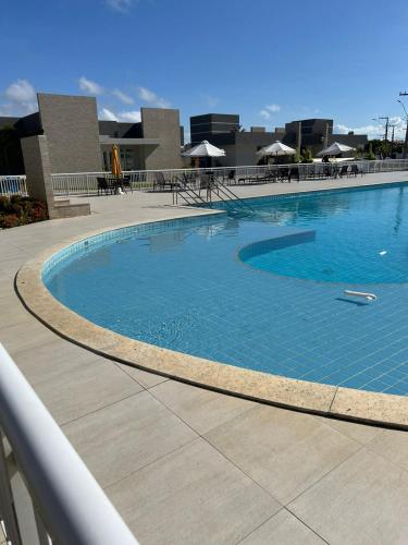 ein großer blauer Pool mit Tischen und Sonnenschirmen in der Unterkunft Casa Condominio Fechado - Barra dos Coqueiros in Barra dos Coqueiros
