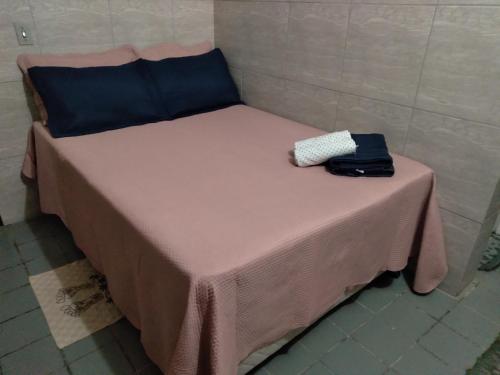 Una cama pequeña con una mesa rosa con una bolsa. en Pousada Pôr do Sol - Galinhos en Galinhos