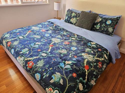 a bed with a blue comforter and pillows at Tranquil and cosy guest house in Oakleigh East