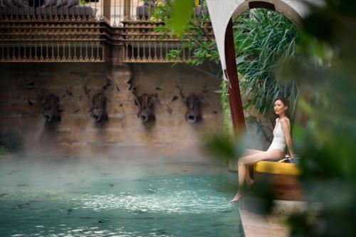 a woman sitting on a barrel in a pool of water at The St. Regis Jakarta in Jakarta