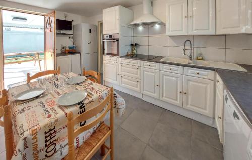 une cuisine avec des armoires blanches et une table avec des chaises dans l'établissement Stunning Home In Mios, à Mios