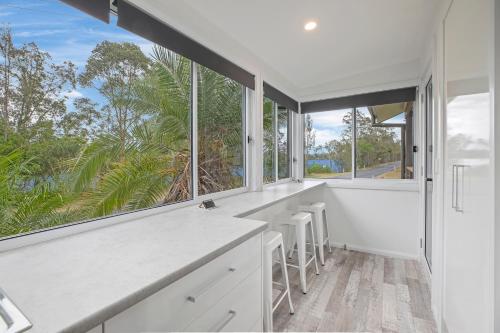 a kitchen with white counters and large windows at The Palm in Mylestom