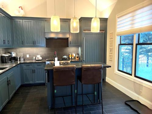 a kitchen with blue cabinets and two bar stools at The Residence on South Oak - steps to the gondola! in Telluride