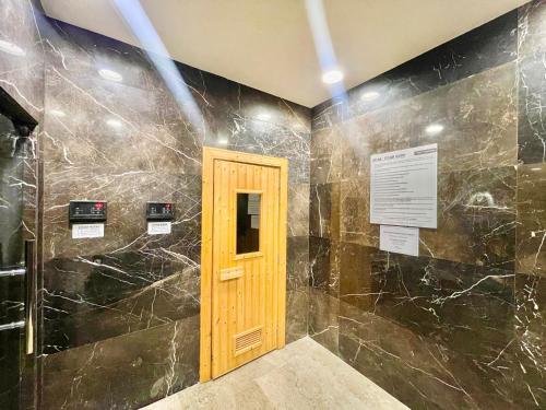 a bathroom with black marble walls and a wooden door at PineTree Puteri Harbour by RR JBcity in Nusajaya