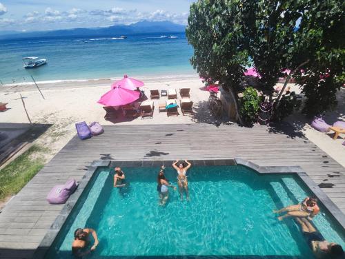 a group of people in a swimming pool next to a beach at Lushy Hostel Nusa Penida in Nusa Penida