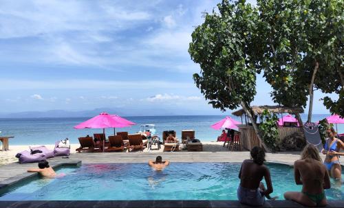 a group of people sitting in a swimming pool next to the beach at Lushy Hostel Nusa Penida in Nusa Penida
