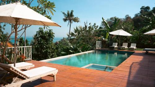 a swimming pool with chairs and an umbrella at La Gautch Bungalow in Nusa Lembongan