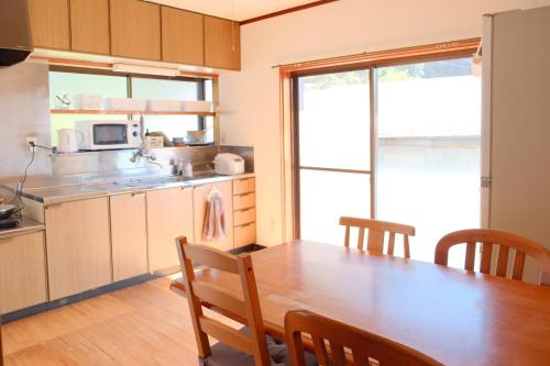 四萬十的住宿－四万十川傍にある日本家屋まるごと「貸切宿　ほとり」，一间带木桌的厨房和一间餐厅
