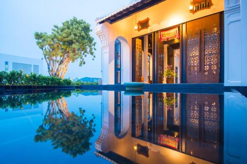 un edificio con su reflejo en el agua en Little Nyonya Hotel, en Phuket