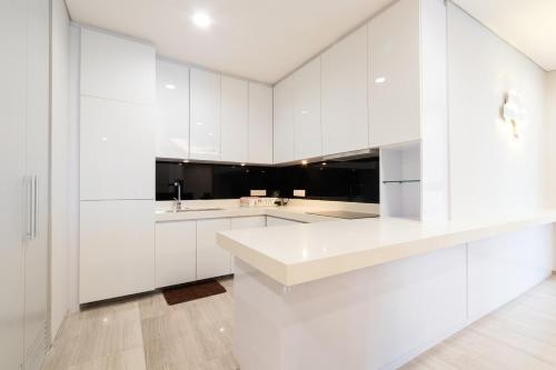 a white kitchen with white cabinets and a sink at PineTree Puteri Harbour by RR JBcity in Nusajaya