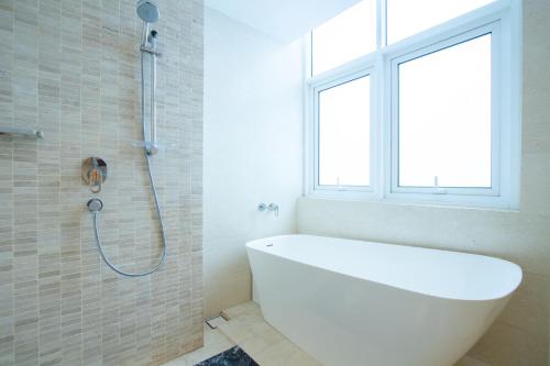 a white bath tub in a bathroom with a window at PineTree Puteri Harbour by RR JBcity in Nusajaya
