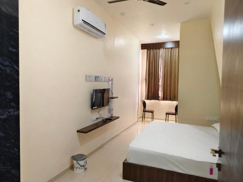 Schlafzimmer mit einem Bett, einem TV und einem Stuhl in der Unterkunft Jawai Rock Hotel in Sheoganj