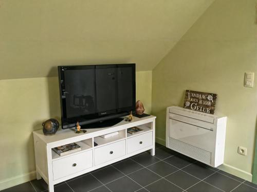 a flat screen tv on a white entertainment center at Hoeve Hulsbeek: genieten van de natuur en de rust in Geetbets