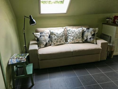 a couch with pillows on it in a room at Hoeve Hulsbeek: genieten van de natuur en de rust in Geetbets