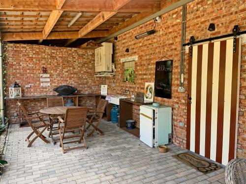 an outdoor kitchen with a table and chairs and a brick wall at Hoeve Hulsbeek: genieten van de natuur en de rust in Geetbets