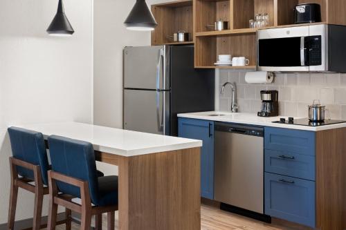 a kitchen with blue cabinets and a refrigerator at Candlewood Suites Richmond - South by IHG in Richmond