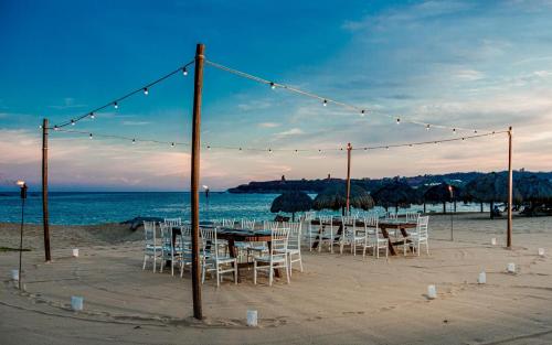 a table and chairs on a beach with lights at Camino Real Zaashila Huatulco in Santa Cruz Huatulco