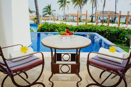 a table and two chairs with a bowl of fruit at Camino Real Zaashila Huatulco in Santa Cruz Huatulco