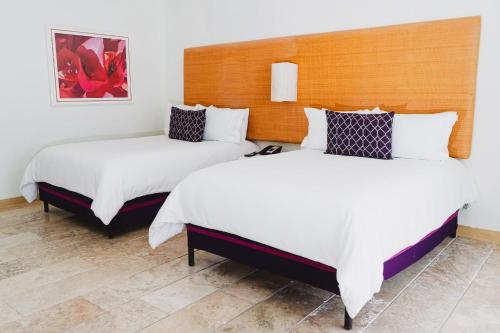 two beds in a hotel room with white sheets at Camino Real Zaashila Huatulco in Santa Cruz Huatulco