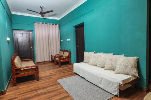 a blue room with a bed and chairs in it at Hill Rows Estate in Vayittiri