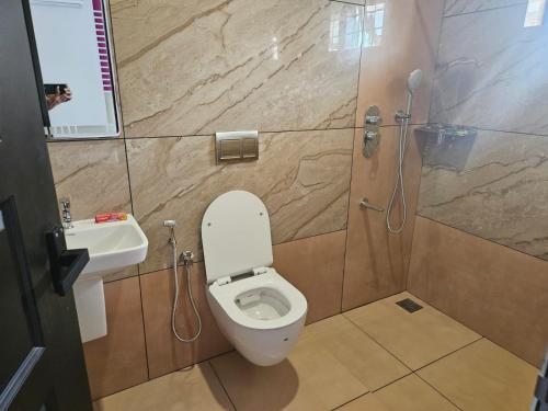 a bathroom with a toilet and a sink and a shower at MATHER RAJAGIRI FURNISHED APARTMENTS in Alwaye