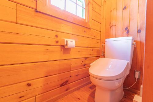a bathroom with a toilet in a wooden wall at 森のや in Shimo-sagano