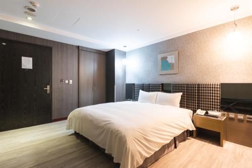 a bedroom with a large white bed and a wooden cabinet at Shianghu Boutique Hotel in Chiayi City