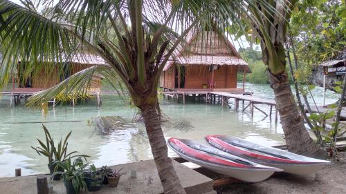 two boats are parked next to a house on the water at Beser Bay Homestay in Besir