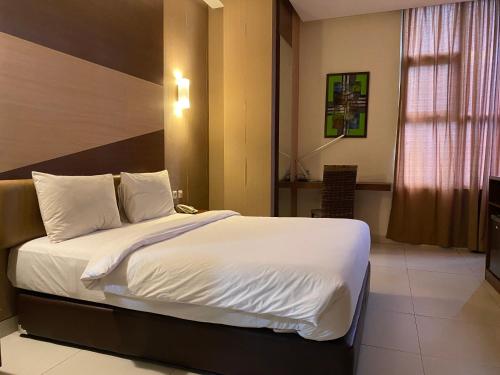 ein Schlafzimmer mit einem großen Bett mit weißer Bettwäsche und Kissen in der Unterkunft LYNT Hotel in Jakarta