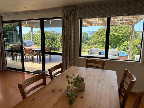 a dining room with a wooden table and a large window at Lake Holiday Home - Spa & Views in Mangakino